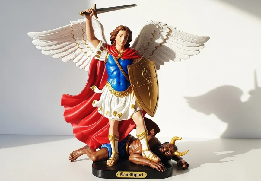 Oración a San Miguel Arcángel para protección del hogar 4 esquinas 10 Oración a San Miguel Arcángel para protección del hogar 4 esquinas: Imagen de San Miguel iluminado por luz lateral, alas desplegadas blancas, túnica azul y capa roja; sostiene espada y escudo mientras pisa al enemigo, símbolo de guardia celestial para cada rincón de casa.
