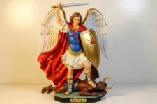 Poderosa Oración a San Miguel Arcángel para protección del hogar 4 esquinas: Estatua policromada de San Miguel con espada alzada y escudo dorado flamígero, manto rojo ondeante, vence al demonio bajo sus pies; ideal para invocar protección en las cuatro esquinas del hogar.
